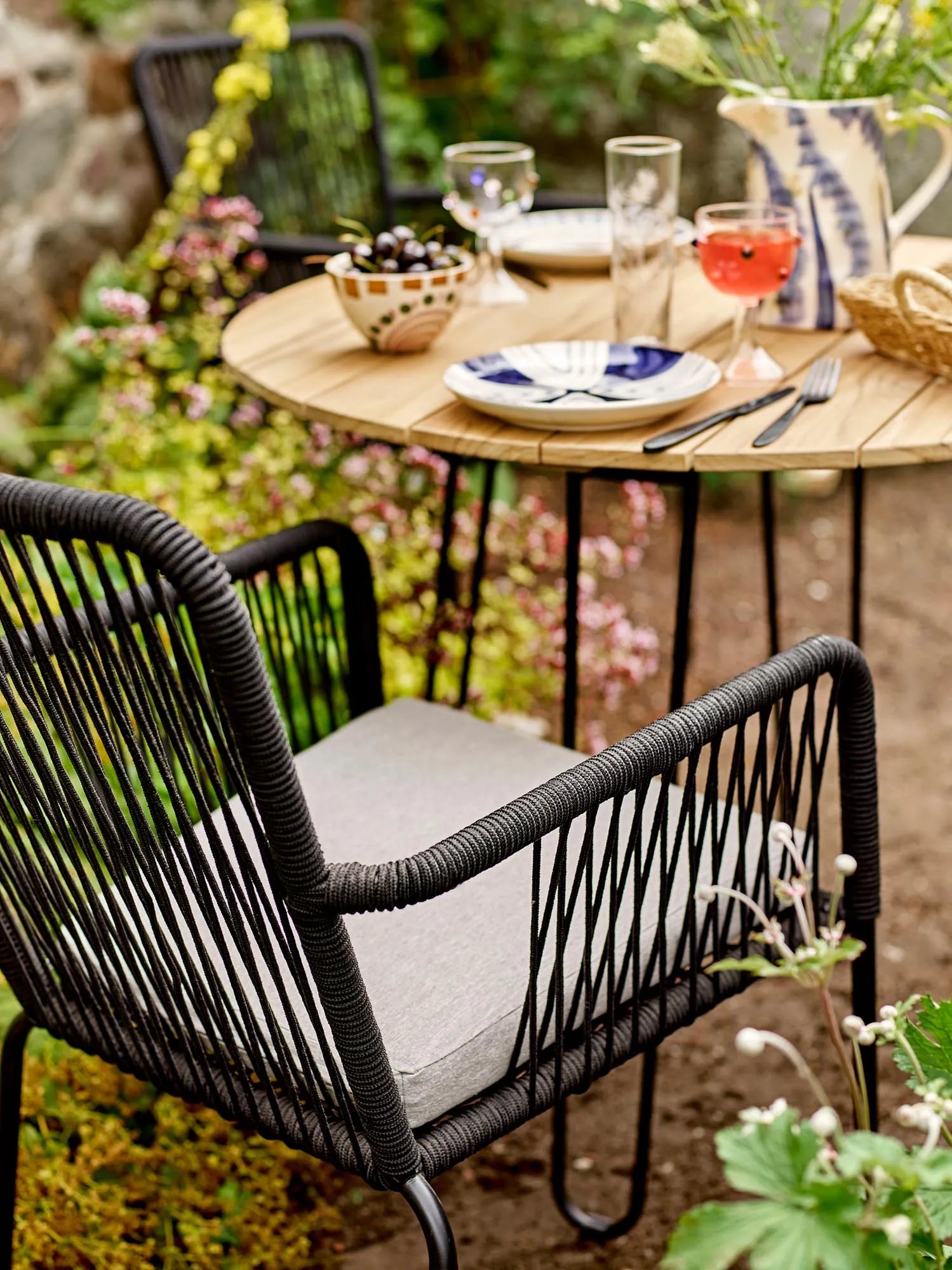 Eleganter Esstisch aus Teakholz mit schwarzem Metallgestell, ideal für stilvolle Outdoor-Dinner.