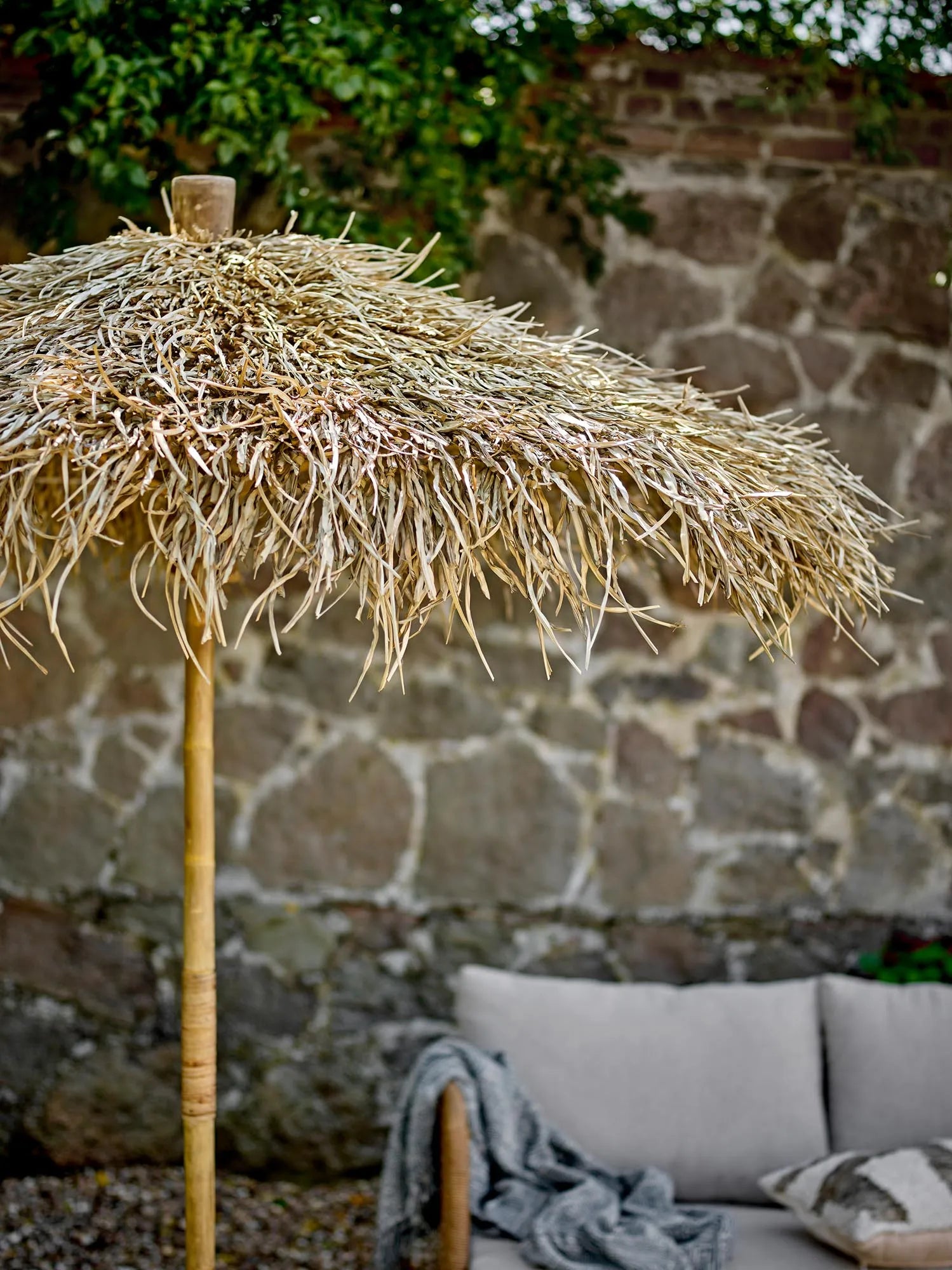 Eleganter Bambus-Sonnenschirm mit Palmblätterdach, bietet natürlichen Schatten und exotisches Flair für Ihren Garten.