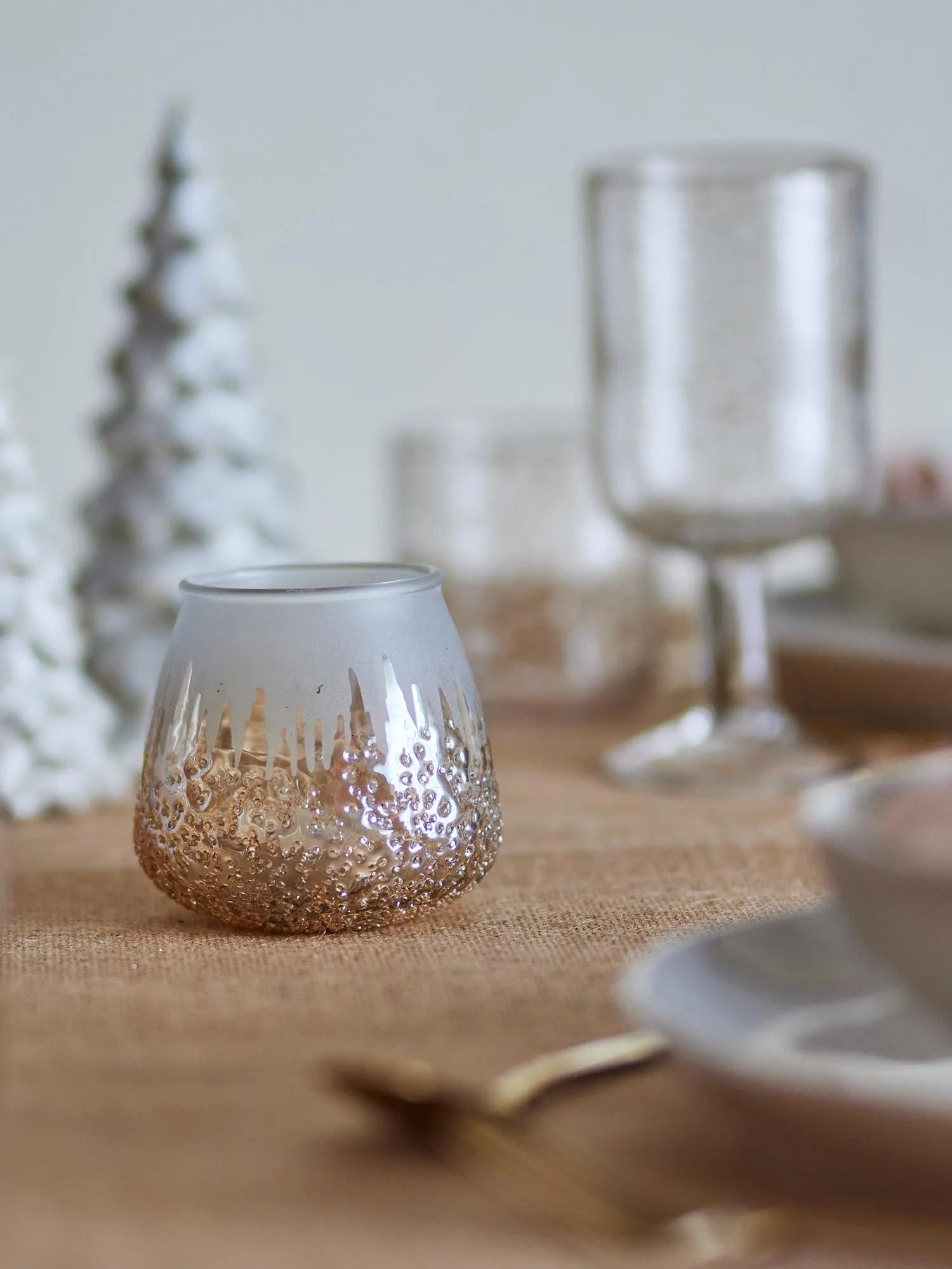 Eleganter Teelichthalter aus recyceltem Glas mit goldenen Akzenten, die warmes Licht reflektieren und Nachhaltigkeit verkörpern.