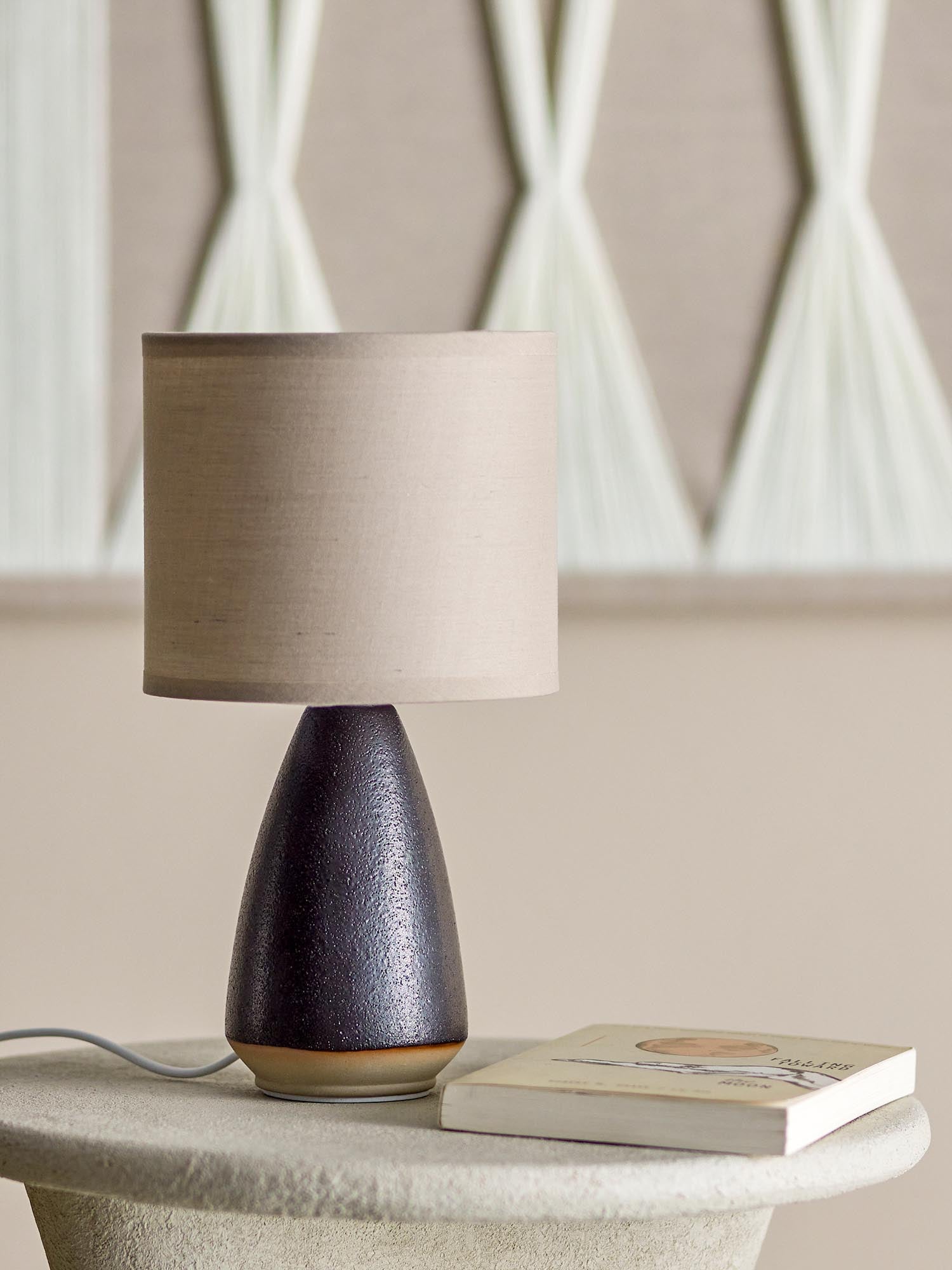 Die Paprica Tischlampe von Bloomingville aus schwarzem Steingut vereint modernes Design mit zeitloser Eleganz.