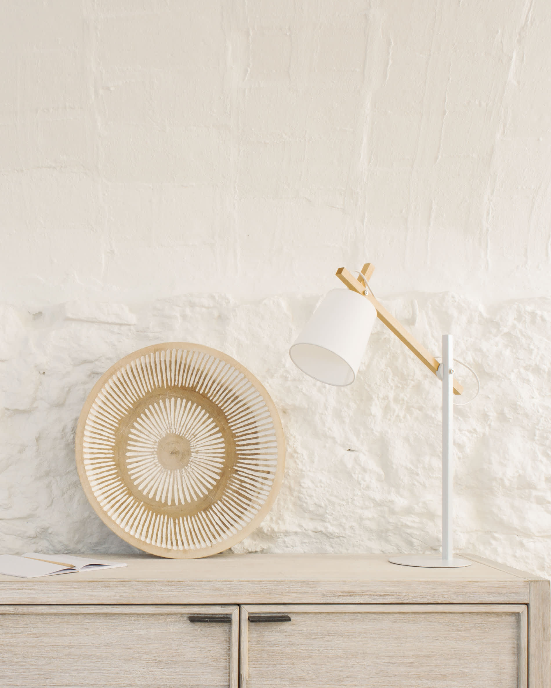 Die Kosta Tischlampe vereint Holz und Metall in einem eleganten Design, das warmes Licht durch einen Baumwollschirm spendet.