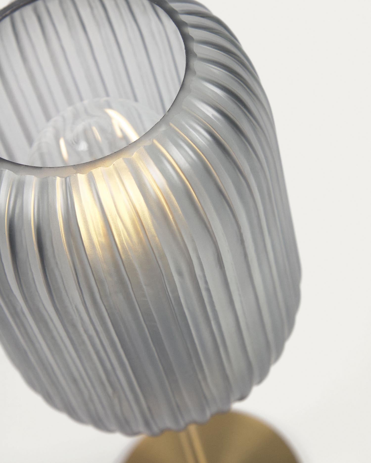 Die Hestia Tischlampe kombiniert ein elegantes Messing-Finish mit grauem Glas, ideal für stilvolle Wohnräume.