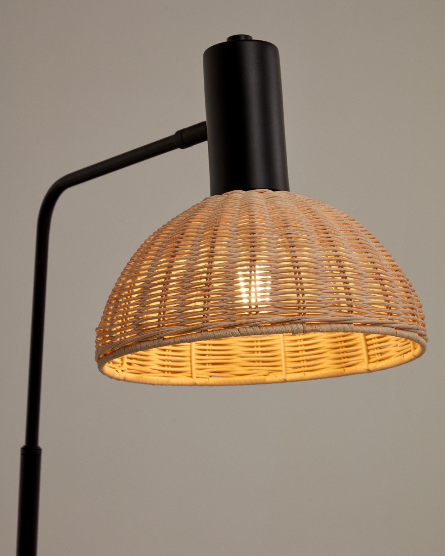 Die Damila Stehleuchte von Kave Home vereint modernes Design mit natürlichem Rattan und schwarzem Metall, ideal für gemütliche Wohnräume.
