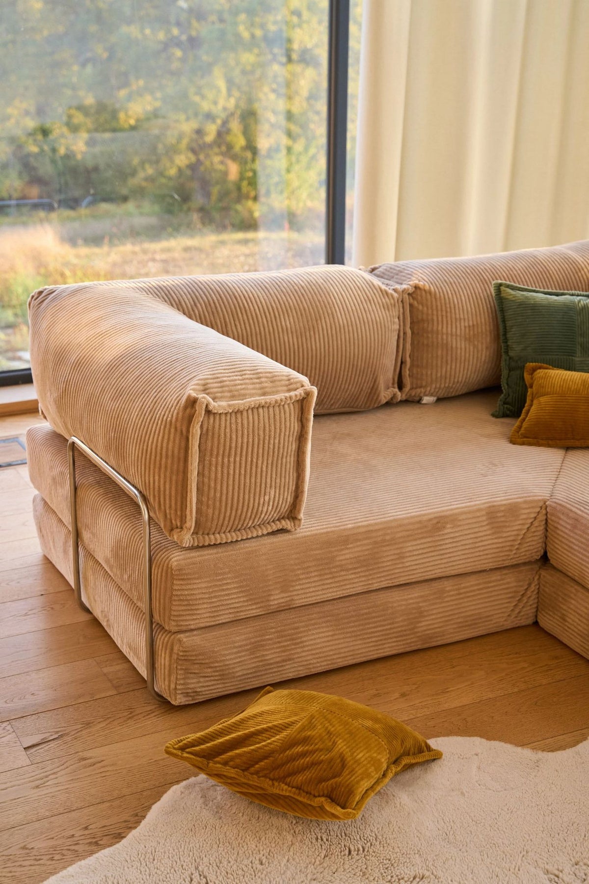 Beiges Eck-Schlafsofa Kanyon von Hanah Home aus geripptem Cord-Plüschstoff, L-Form mit vier Kissen, auf hellem Untergrund fotografiert.