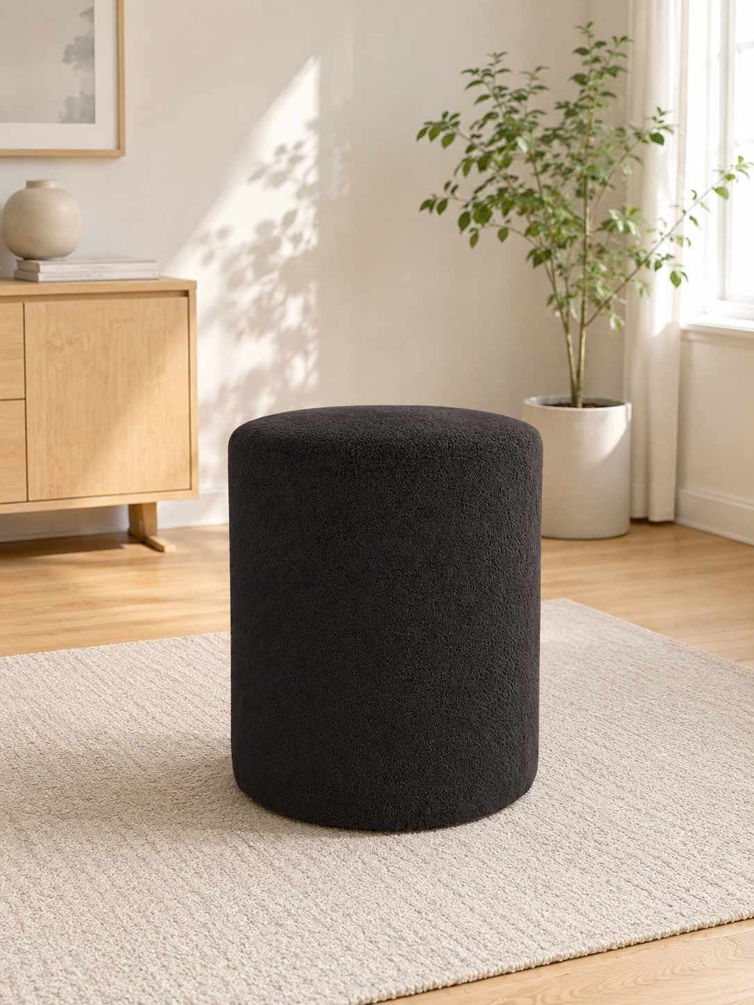 Runder Pouf in Anthrazit von Hanah Home mit Wellsoft-Stoff-Bezug, Kunststoffbeinen und Sitzfläche aus melaminbeschichteter Spanplatte.