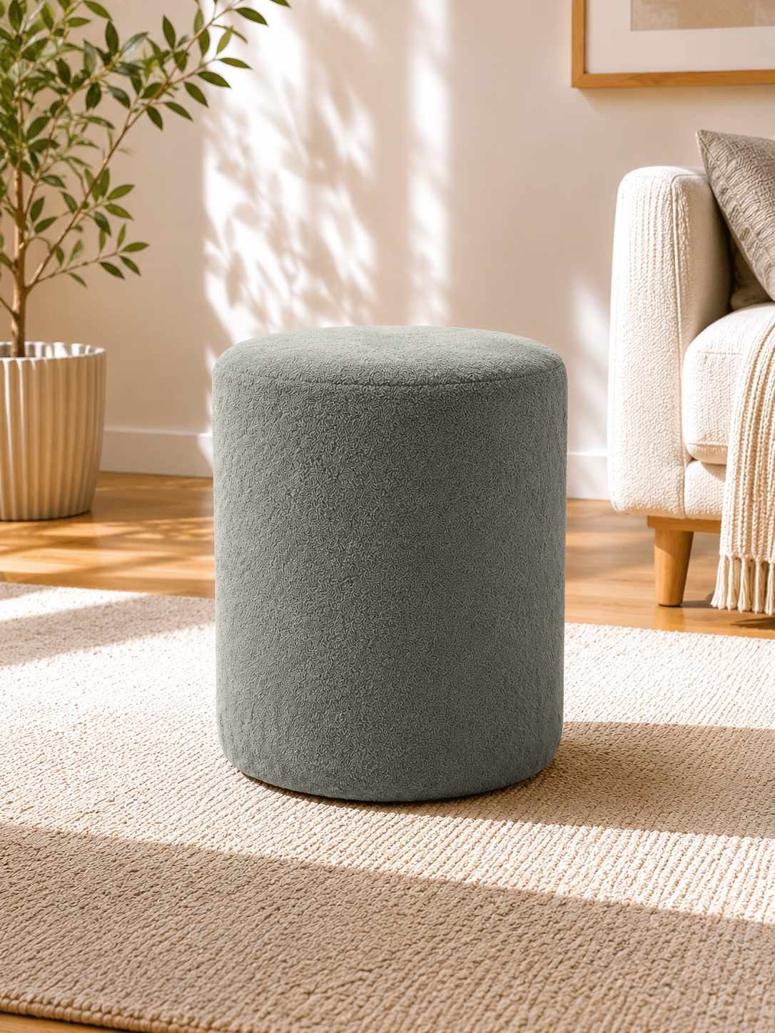 Runder Pouf in Steingrau mit Wellsoft-Stoffbezug, Spanplatten-Sitzfläche und kurzen Kunststoffbeinen, Durchmesser 40 cm, Höhe 45 cm.
