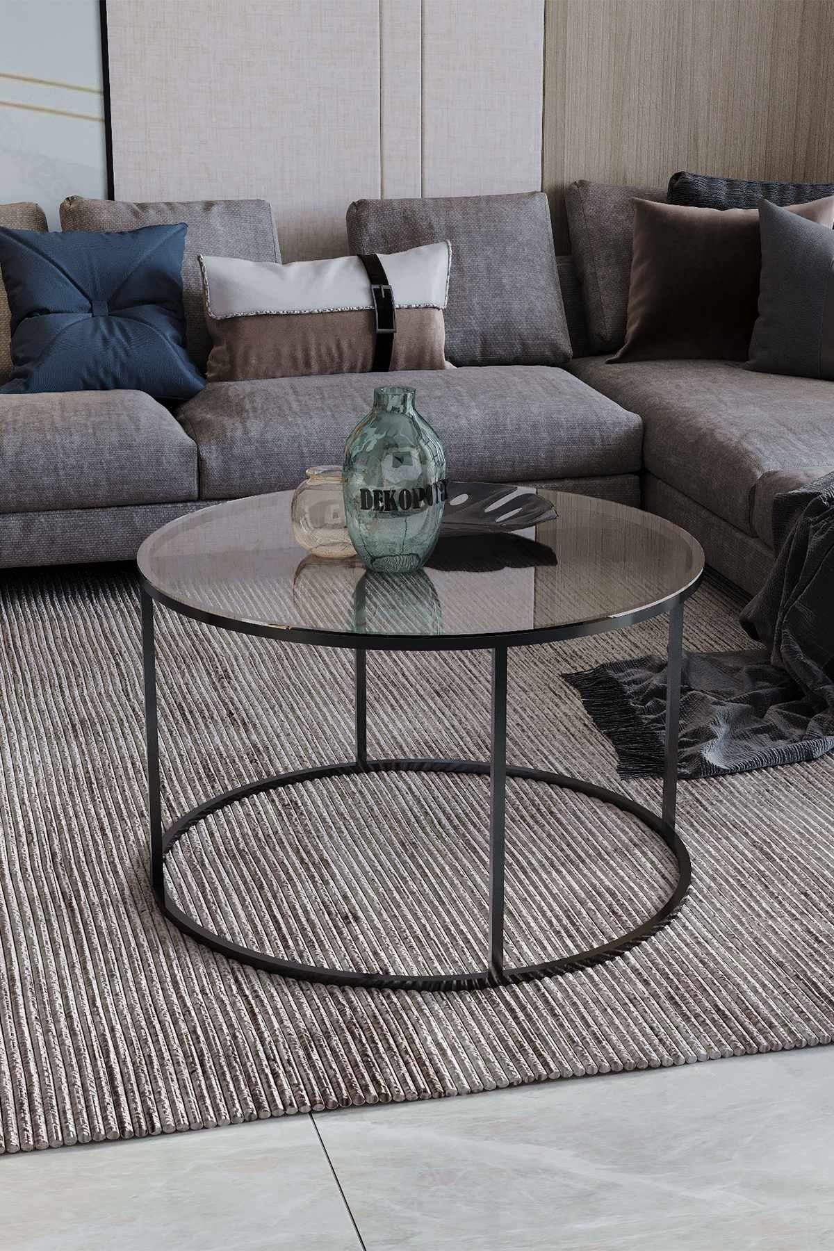 Runder Couchtisch mit schwarzem Eisengestell und runder Sicherheitsglasplatte, Durchmesser 75 cm, Höhe 45 cm, freistehend im Raum.