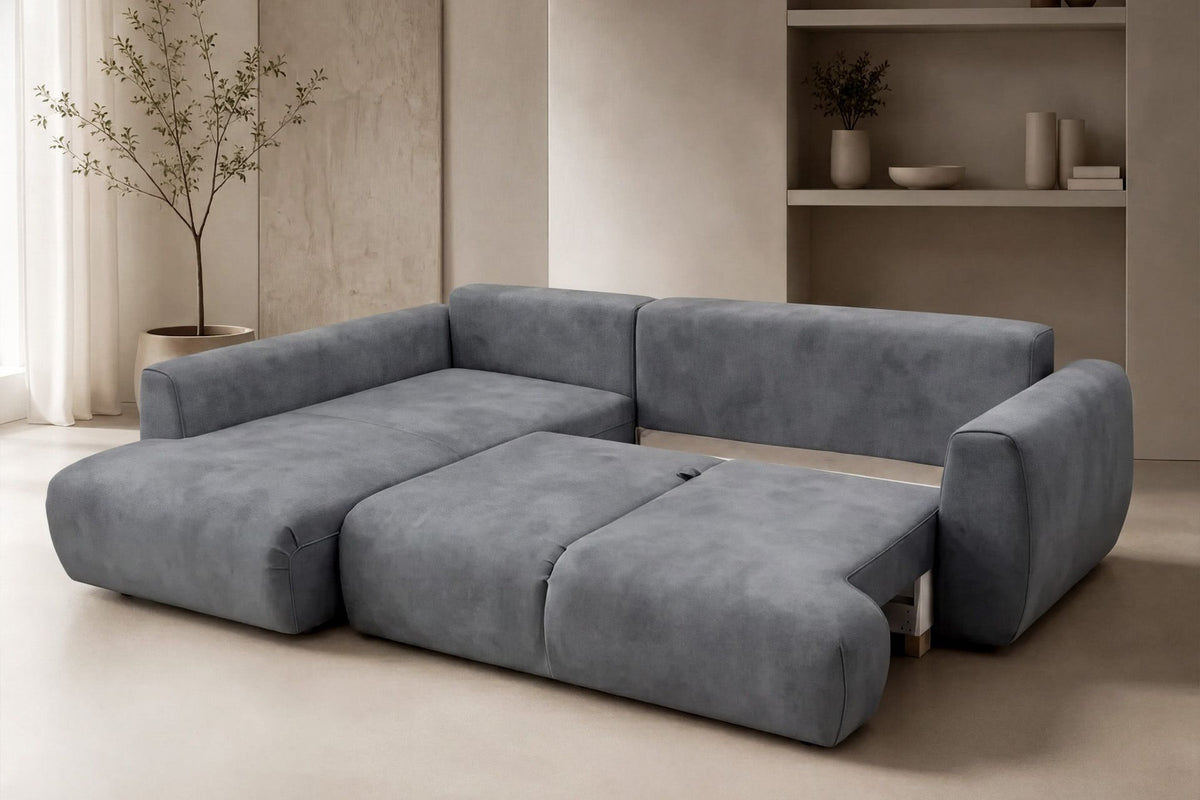 Graues Ecksofa Arthur mit Schlaffunktion, Gestell aus Buchenholz und Spanplatte, Bezug aus Polyester, Kunststoffbeine, zwei Kissen sichtbar.