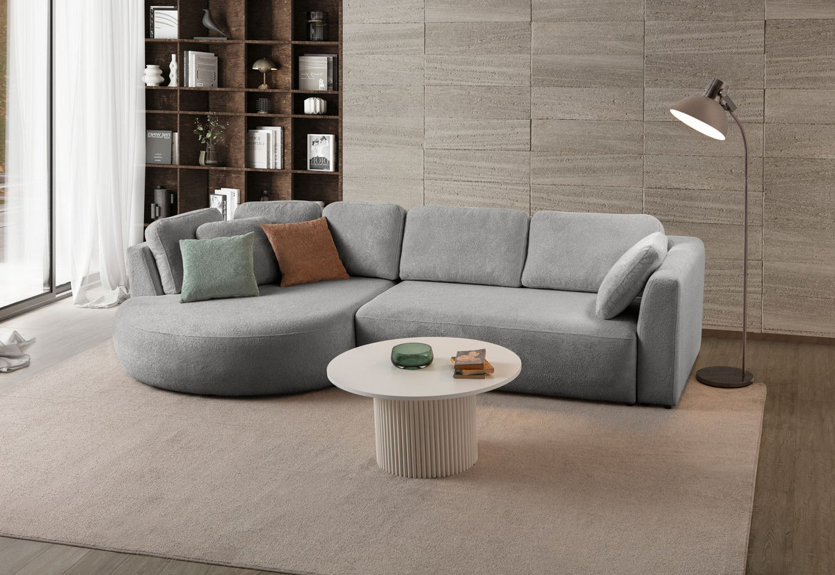 Graues Ecksofa Venezia links von Hanah Home mit Polyesterbezug, Hainbuche-Gestell, Kunststoffbeinen und neun Kissen im Wohnraum.