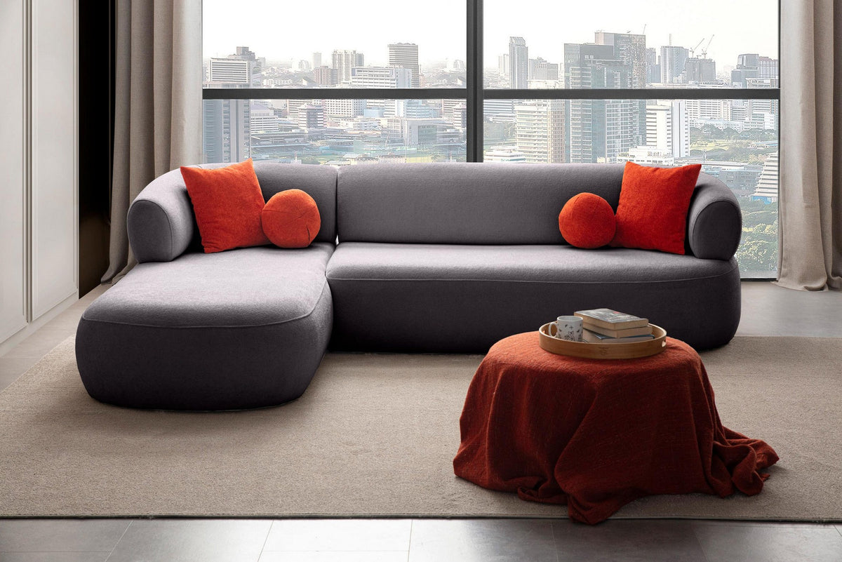 Dunkelgraues Ecksofa Roma von Hanah Home mit Boucle-Stoffbezug, Kunststoffbeinen und vier losen Kissen, links ausgerichtet.