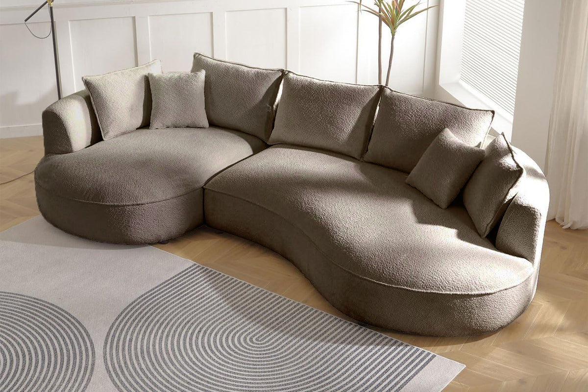 Ecksofa links in Farbe Mink mit Boucle-Stoffbezug, Kunststoffbeinen und sieben Kissen, Grundriss L-Form, Sitztiefe 88 und 124 cm.