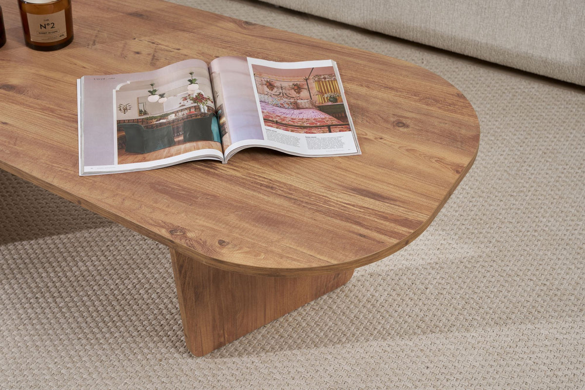 Ovaler Couchtisch in Atlantik-Kiefer Optik von Nordure aus melaminbeschichteter Spanplatte, 130 cm breit, 65 cm tief, 40 cm hoch, im Wohnraum platziert.