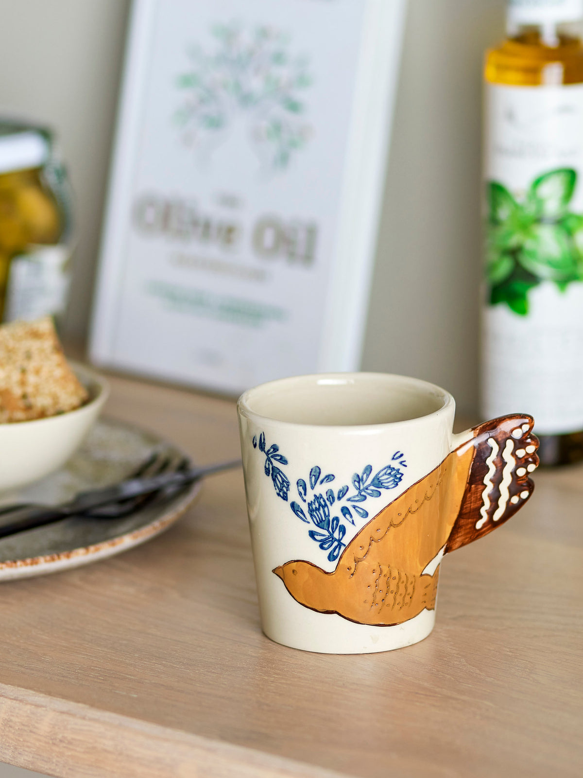 Beige Tasse aus Steinzeug der Serie Hezha von Bloomingville mit handverzierter Vogel-Illustration und Henkel in Vogelschwanz-Form