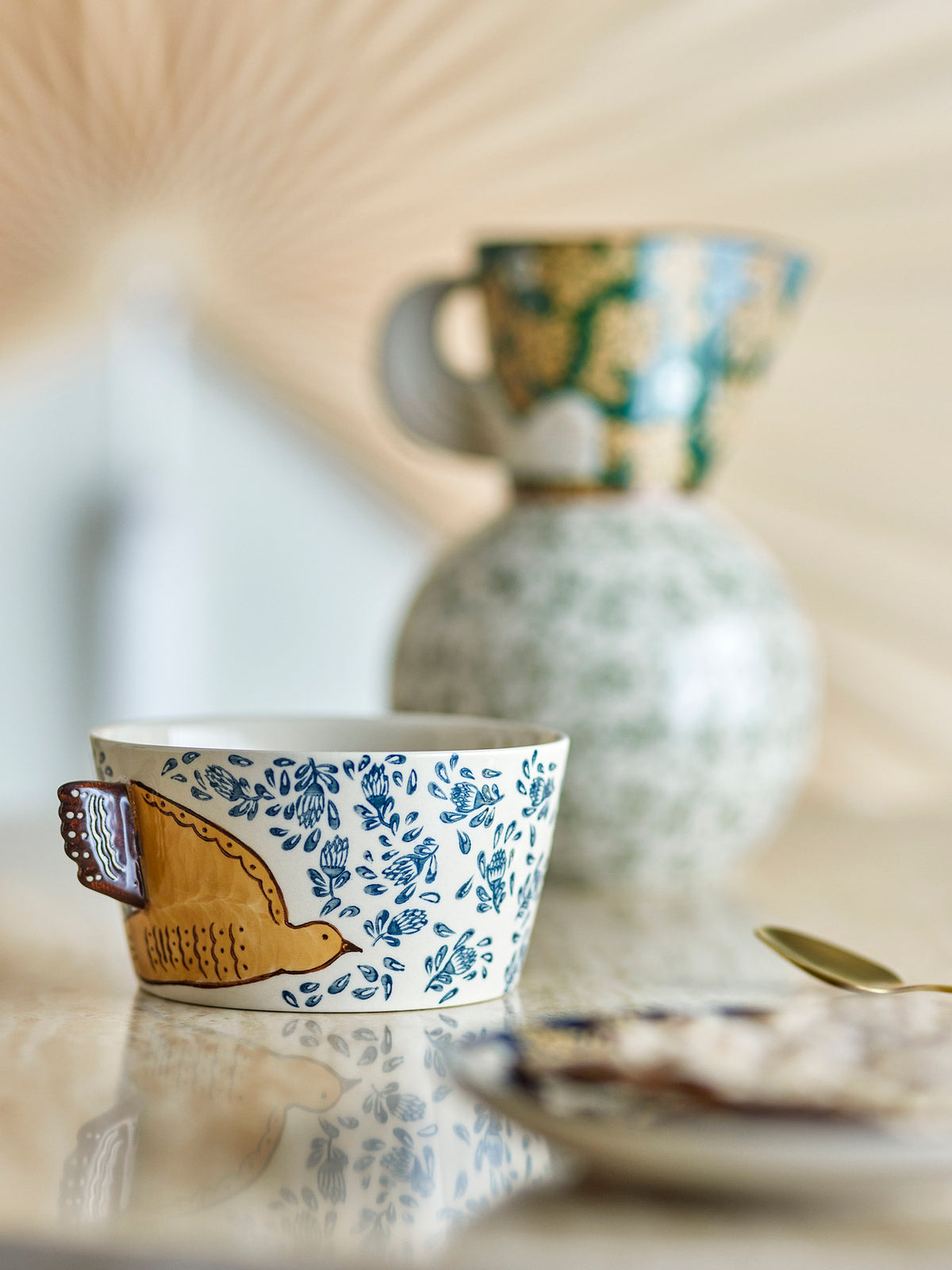 Runde Schale aus Steingut in Beige mit handverzierten Vogel- und Blumenmotiven in Blau- und Brauntönen, Modell Hezha von Bloomingville