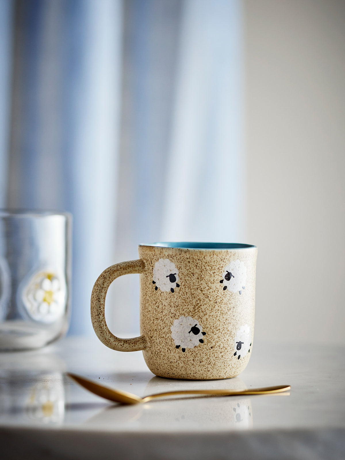 Beige Tasse aus Steingut mit gesprenkelter Oberfläche und weissen Schafmotiven, Serie Dolly von Bloomingville Mini, rund mit Henkel.