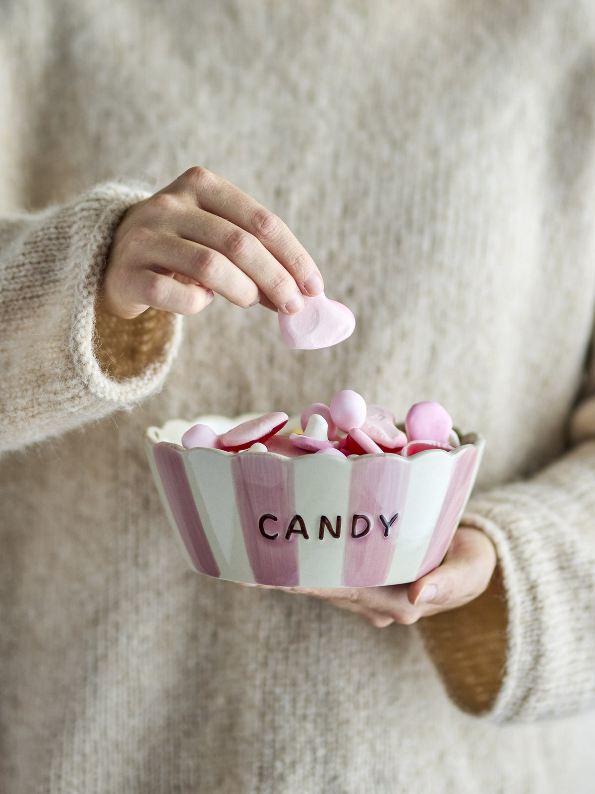 Rosafarbene Steingutschale mit gewelltem Rand, handbemalten vertikalen Streifen aussen und feinen Punkten innen, Schriftzug CANDY an der Seite.