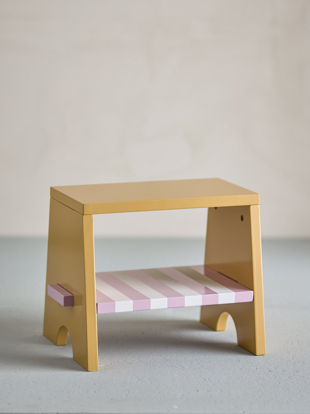 Liova Hocker von Bloomingville Mini aus lackiertem MDF, hellgelber Rahmen mit rosafarbenen Streifen auf der Sitzfläche, kleine Sitzgelegenheit.