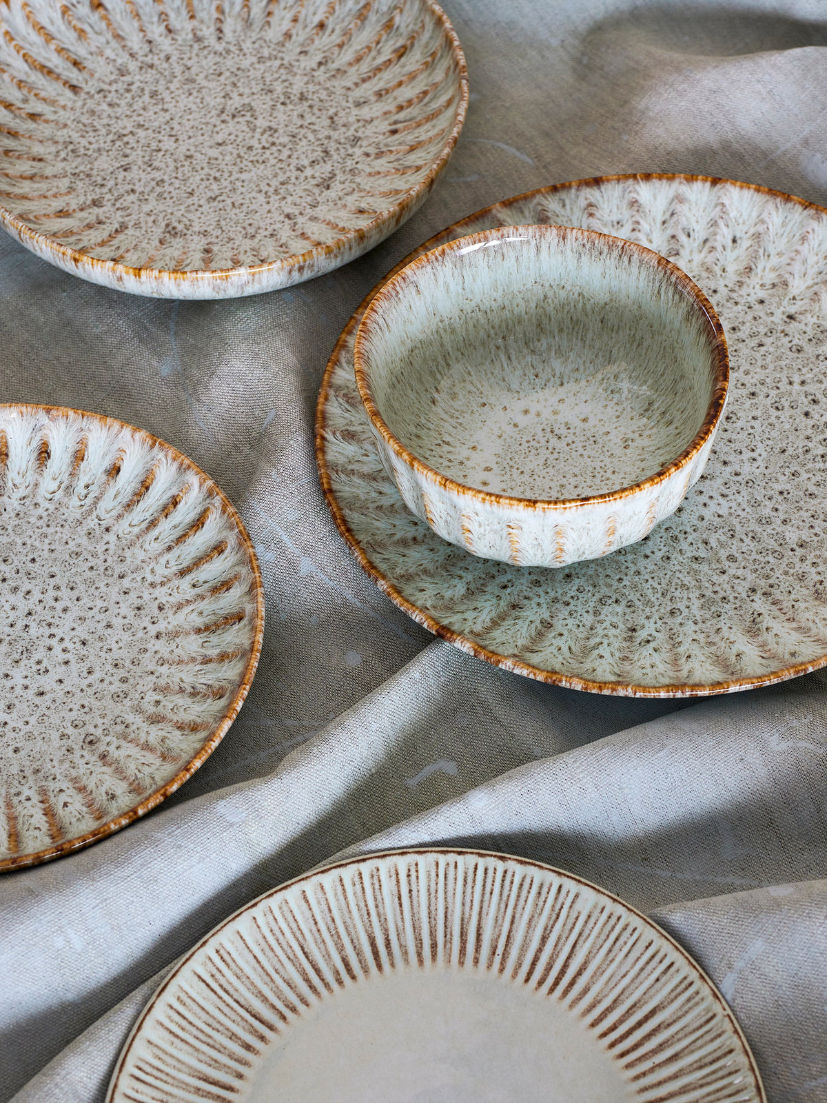 Runde Schale aus Steingut in Beige mit reaktiver Glasur, weiche Form, Serie Fleur von Creative Collection, auf hellem Hintergrund fotografiert