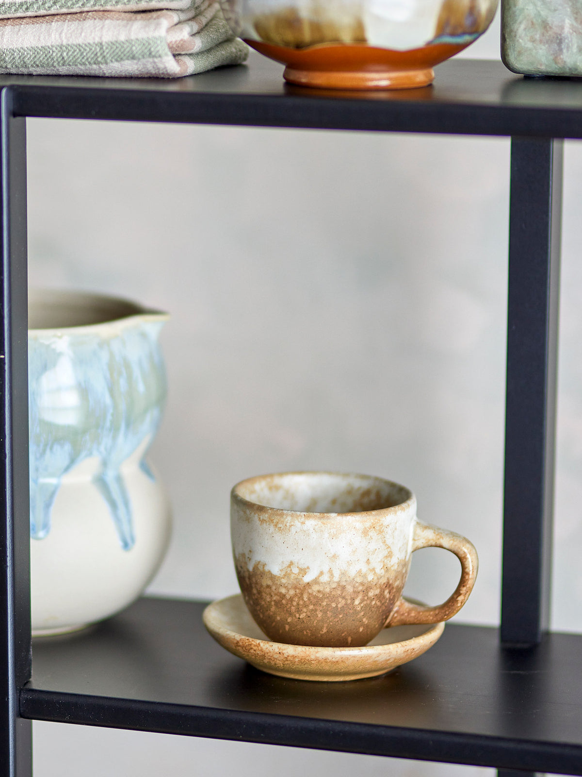 Beige Tasse mit Untertasse aus Steingut der Serie Brenta von Bloomingville, runde weiche Form mit reaktiver Glasur in Beigetönen.