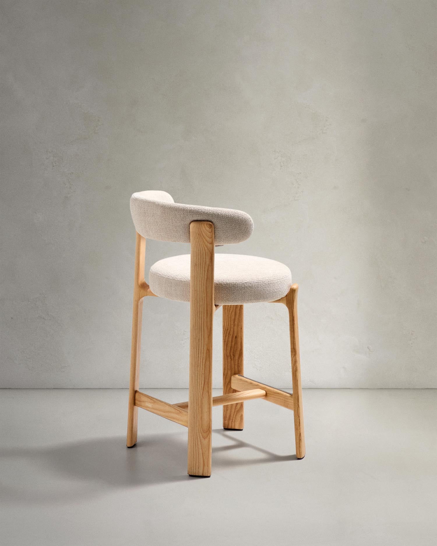 Erleben Sie den Hocker Granite von Kave Home: Bequeme Chenille trifft auf robustes Eschenholz in einem eleganten skandinavischen Stil.