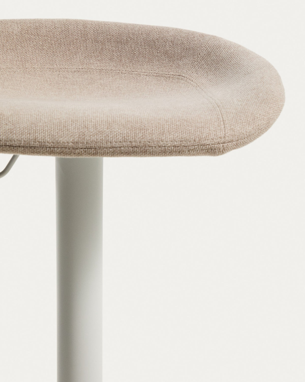 Runder Hocker mit beigem Chenillebezug, gepolstertem Sitz und mattweissem Stahlgestell mit rundem Fussring, freigestellt fotografiert.