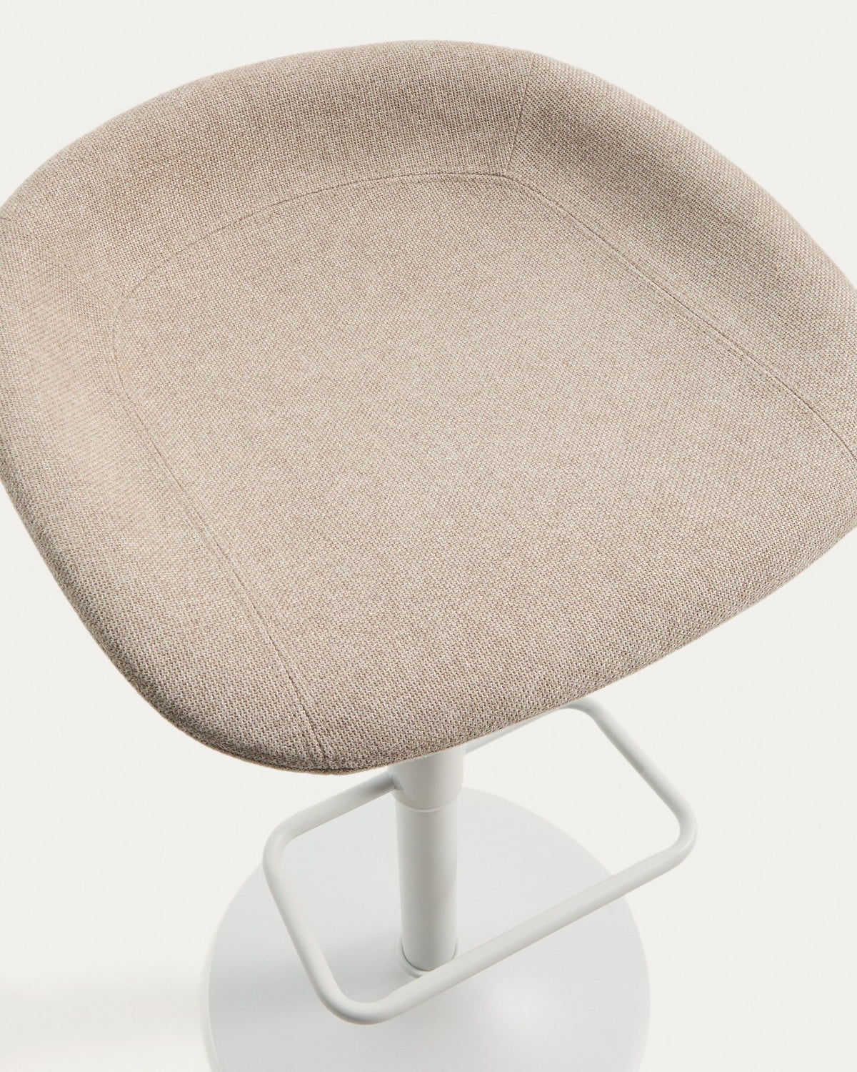 Runder Hocker mit beigem Chenillebezug, gepolstertem Sitz und mattweissem Stahlgestell mit rundem Fussring, freigestellt fotografiert.