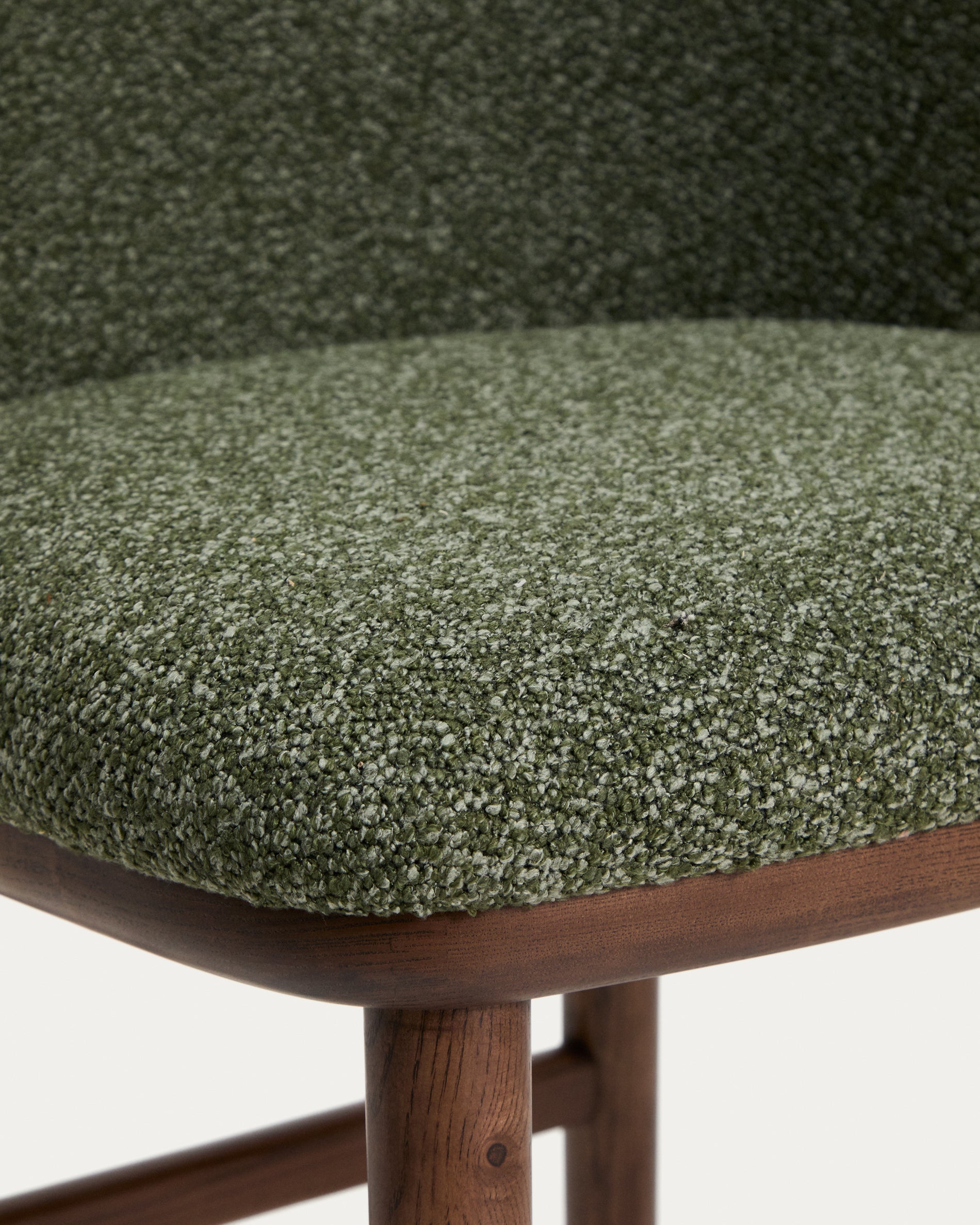 Eleganter Hocker Ciselia aus dickem, dunkelgrünem Chenille, ausgestattet mit stabilen Eschenholzbeinen in Walnussholzoptik, ideal für stilvolle Sitzgelegenheiten.