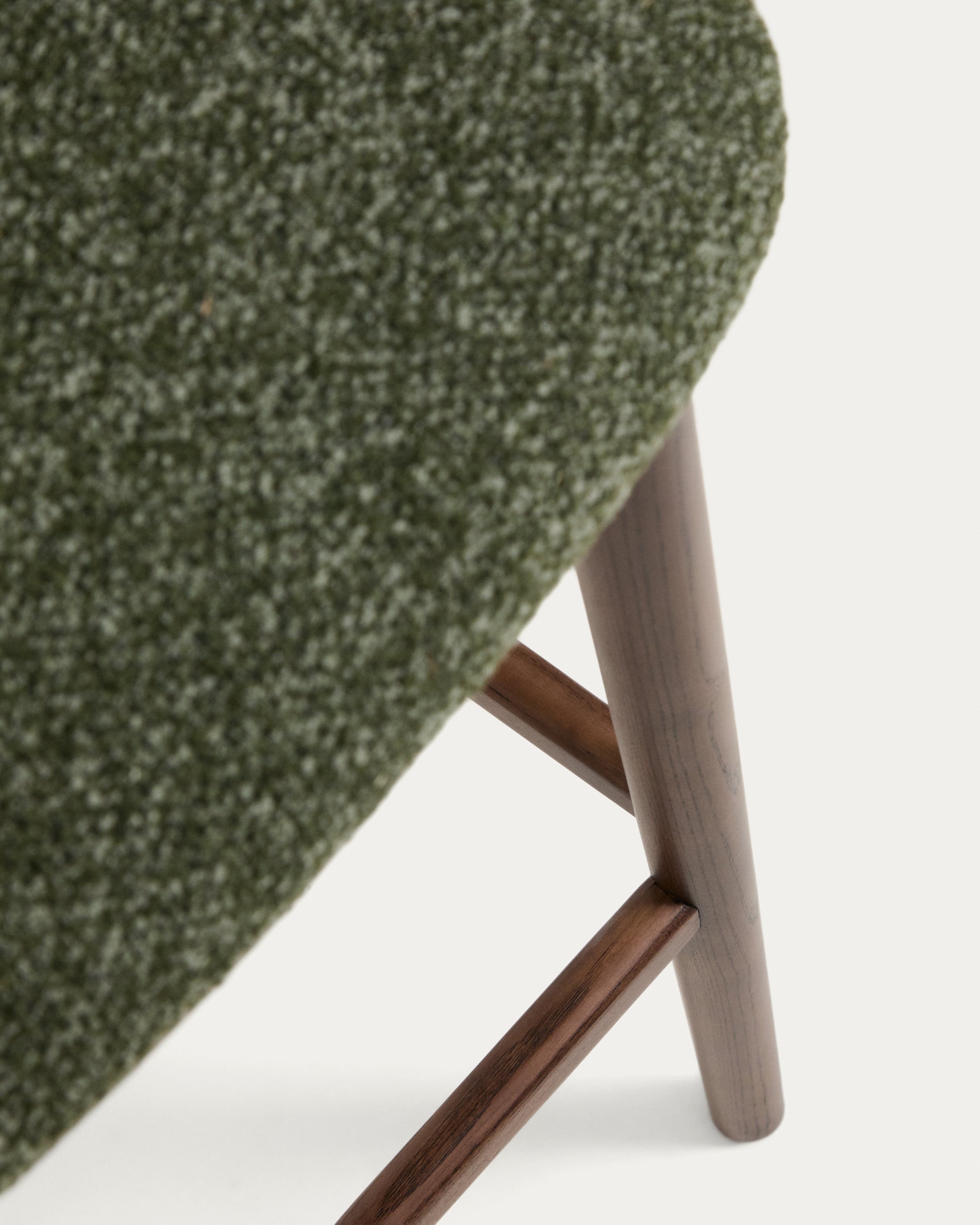 Eleganter Hocker Ciselia aus dickem, dunkelgrünem Chenille, ausgestattet mit stabilen Eschenholzbeinen in Walnussholzoptik, ideal für stilvolle Bars.