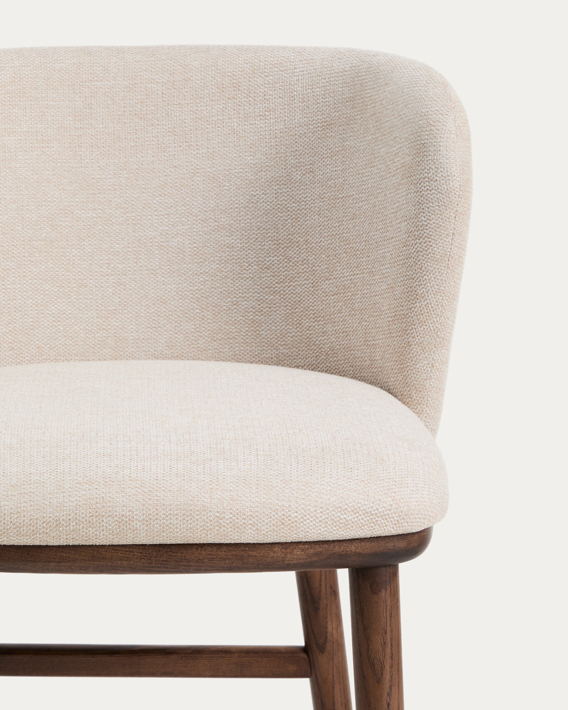 Beiger Chenille-Hocker Ciselia mit robusten Eschenholzbeinen in edler Walnussholzfarbe, perfekt für moderne Barbereiche.