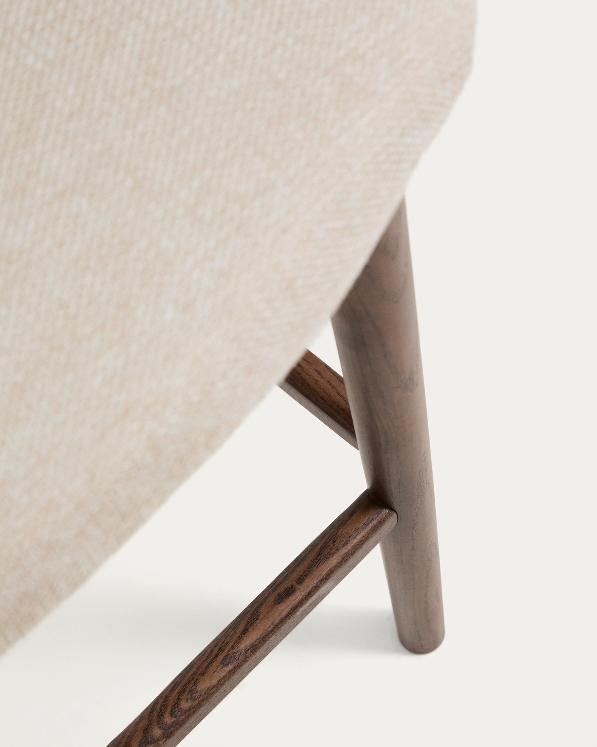Eleganter Hocker Ciselia in beigem Chenille, ausgestattet mit stabilen Eschenholzbeinen in Walnussholzoptik, ideal für stilvolle Sitzgelegenheiten.