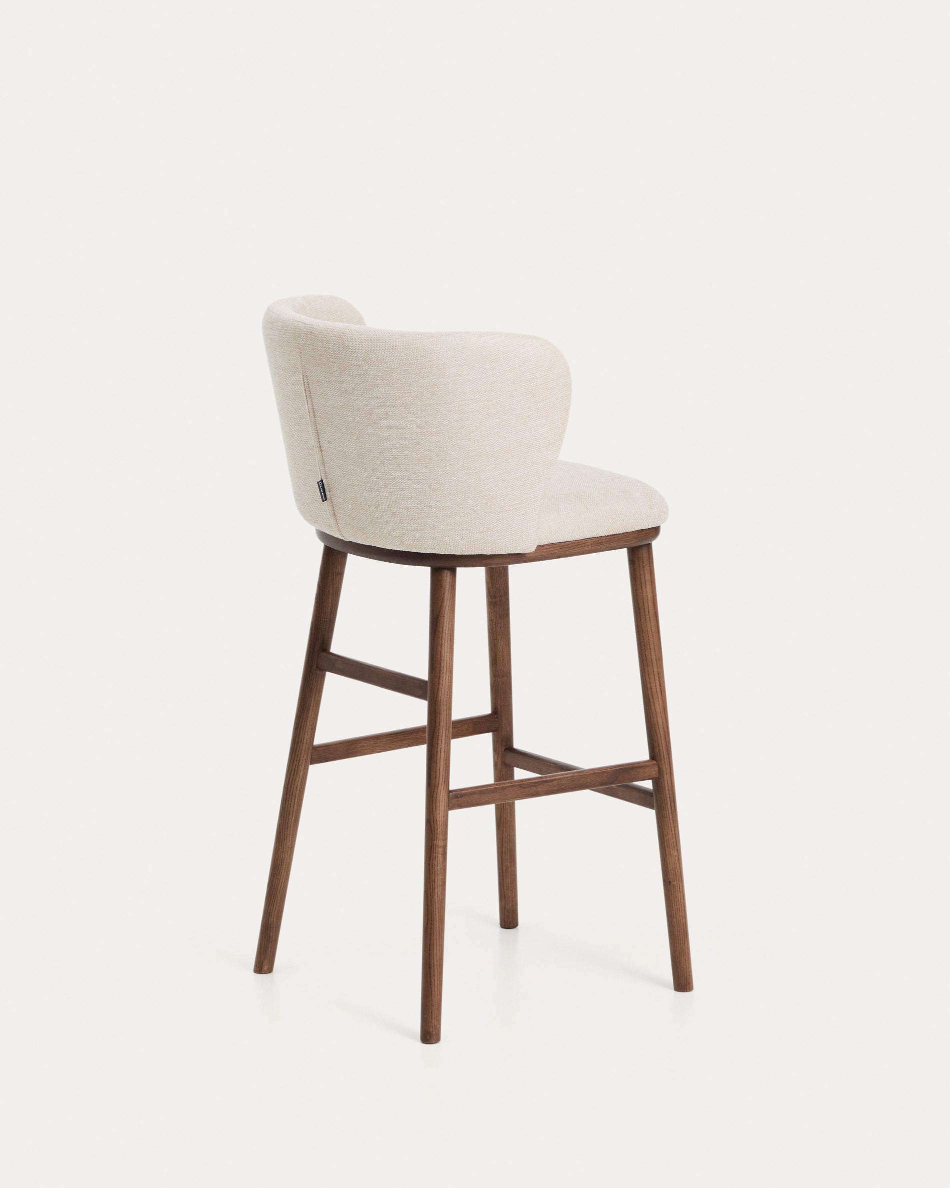 Beiger Chenille-Hocker Ciselia mit robusten Eschenholzbeinen in Walnussholzfarbe, perfekt für moderne Bars und gemütliche Wohnbereiche.