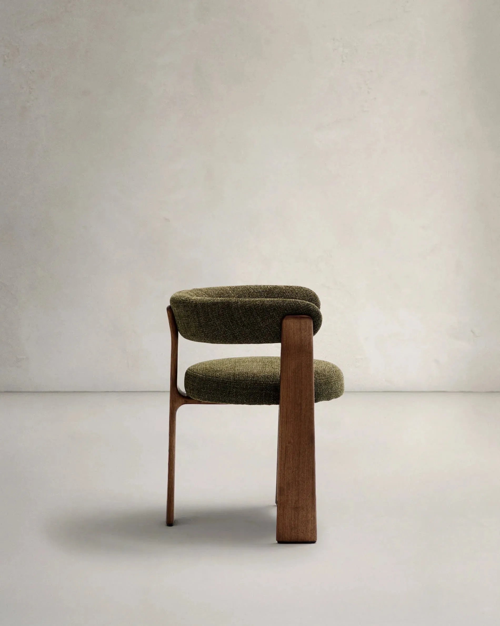 Eleganter Stuhl mit grünem Chenille-Stoff, dreibeinigem Eschenholzgestell in Walnussoptik, FSC-zertifiziert, von Kave Home.
