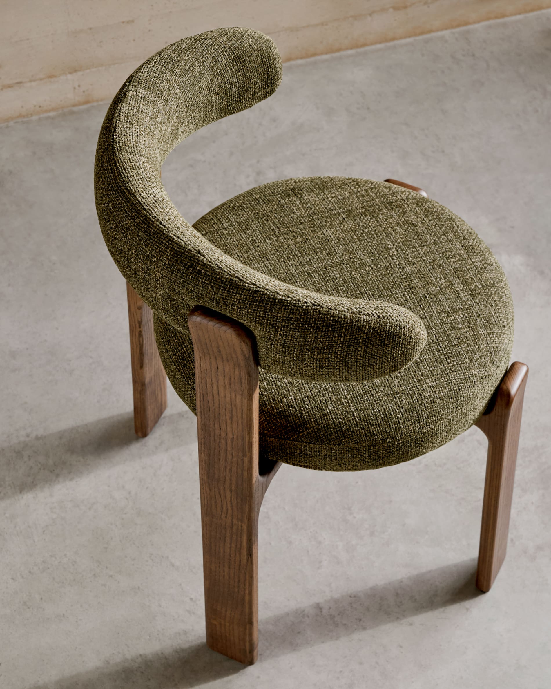 Moderner Stuhl aus grüner Chenille und FSC-zertifiziertem Eschenholz mit Walnuss-Finish, verbindet Komfort und umweltbewusstes Design.