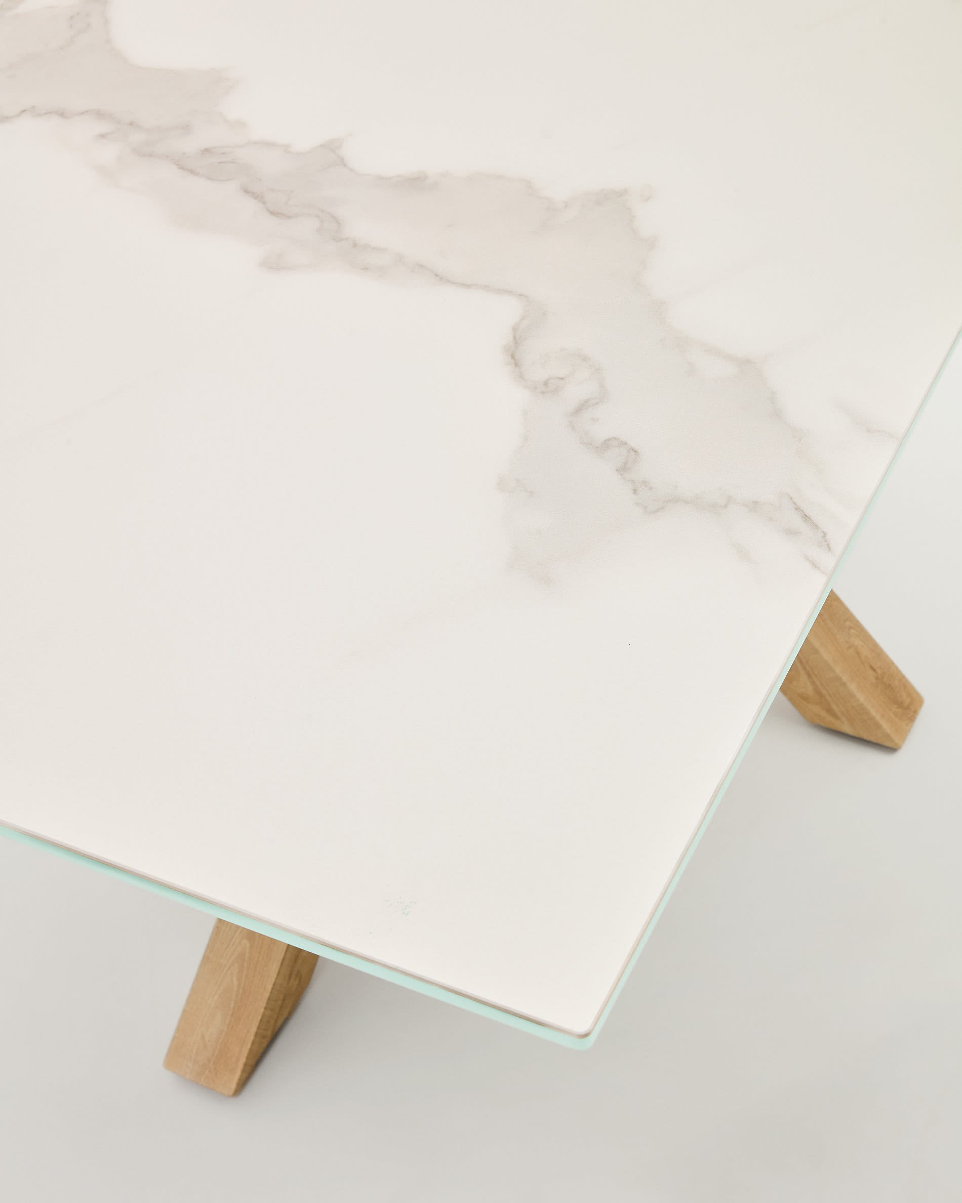 Der Tisch Argo von Kave Home kombiniert stilvolles Design mit praktischen Eigenschaften: Weiße Kalos-Porzellanplatte und stabile Stahlbeine in Holzoptik, 180 x 100 cm.