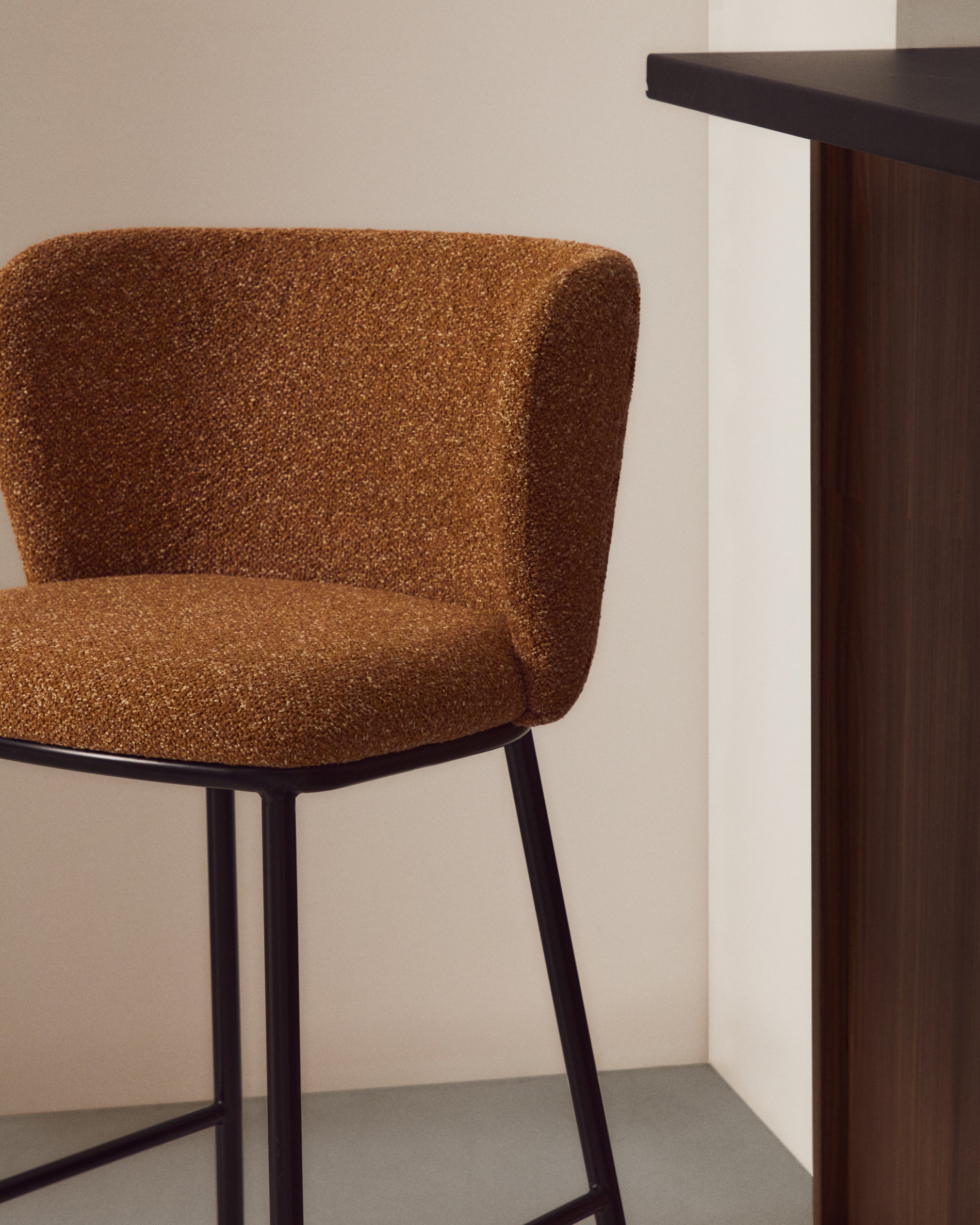 Stylischer Hocker Ciselia aus weichem Chenille in warmem Terrakotta, unterstützt von stabilen, schwarz lackierten Stahlbeinen, perfekt für moderne Wohnräume.