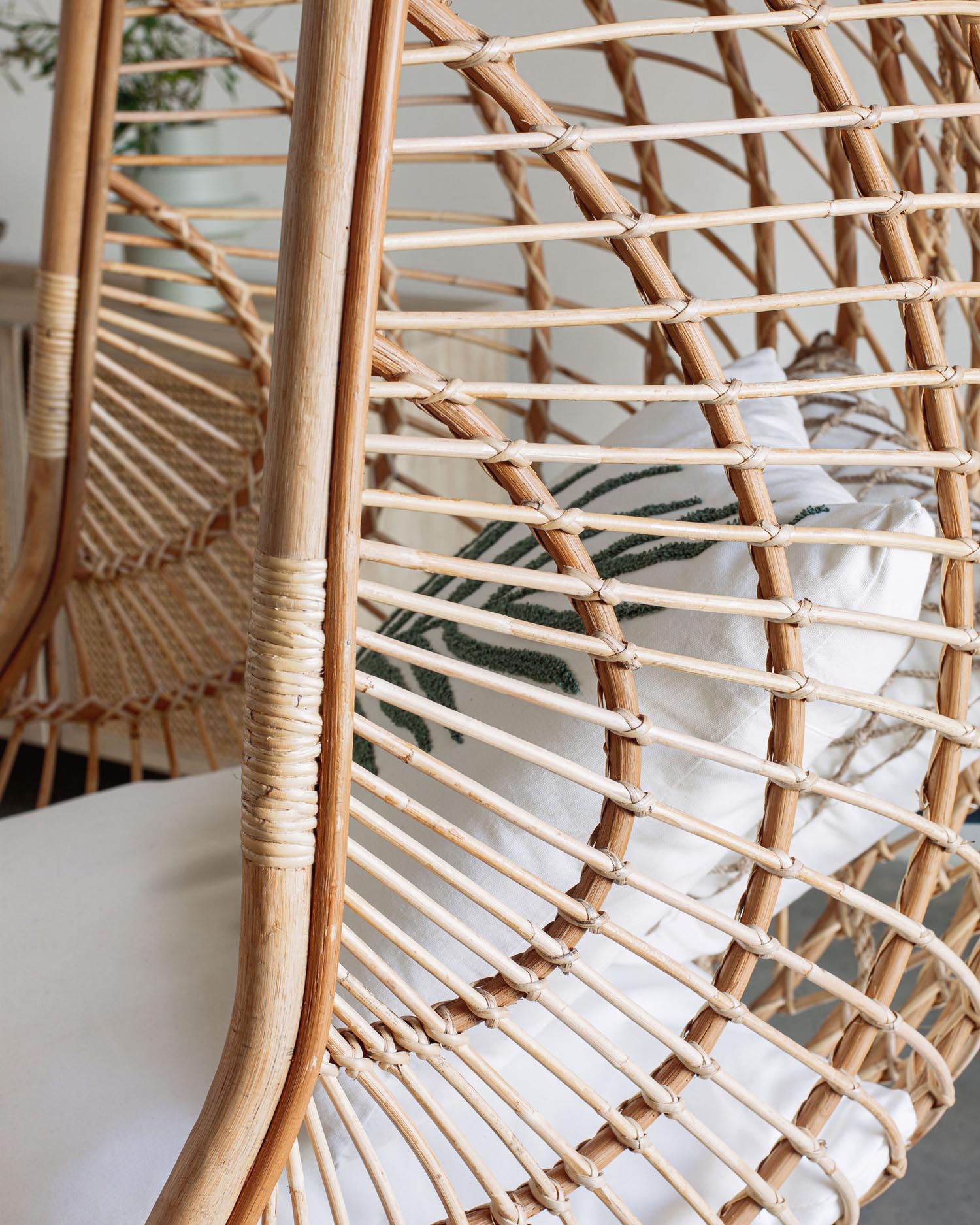 Eleganter Rattan-Hängesessel mit stabilem Metallgestell, ideal für stilvolle Entspannung in Innenräumen oder überdachten Außenbereichen.