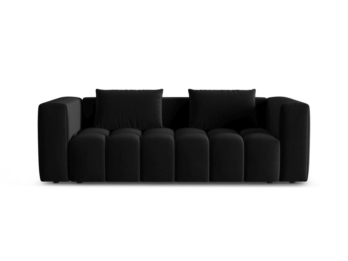 Sandfarbenes Samt-Bettsofa Verona mit drei Sitzplätzen, ausklappbarer Liegefläche, Bettkasten und schwarzen Kunststoffbeinen im Wohnraum.