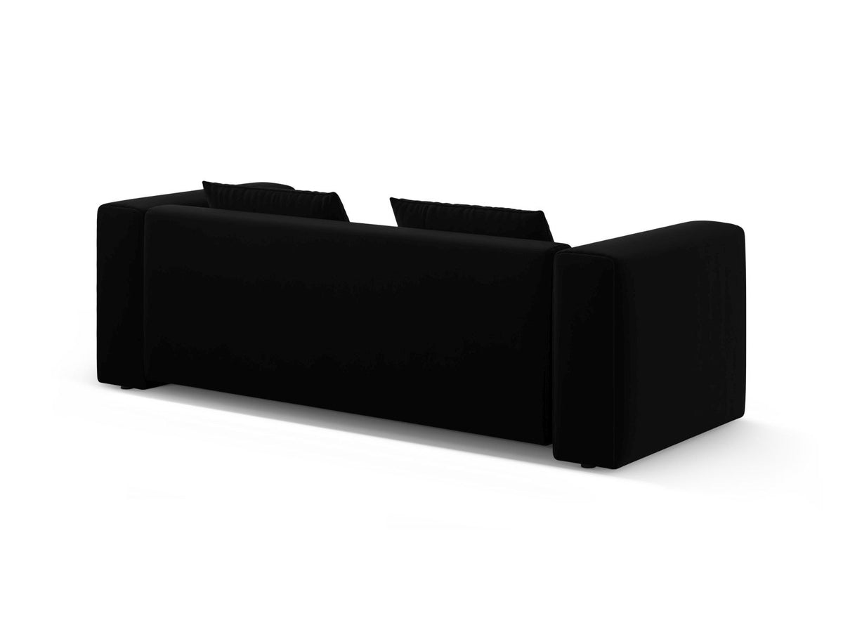 Sandfarbenes Samt-Bettsofa Verona mit drei Sitzplätzen, ausklappbarer Liegefläche, Bettkasten und schwarzen Kunststoffbeinen im Wohnraum.