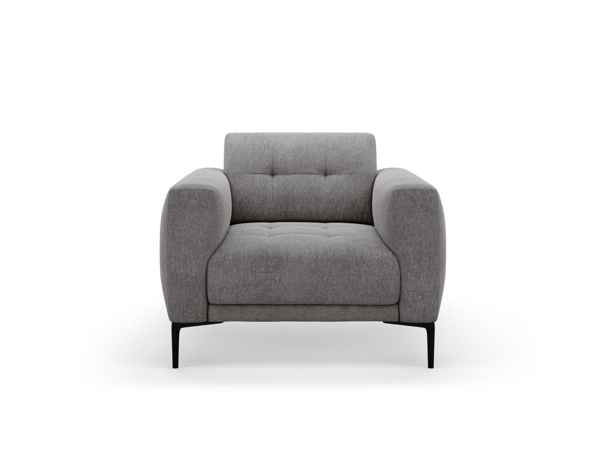 Beige gepolsterter Sessel mit Sorella-Stoffbezug, schwarzen Metallbeinen und Massivholzrahmen, Frontalansicht auf weissem Hintergrund.