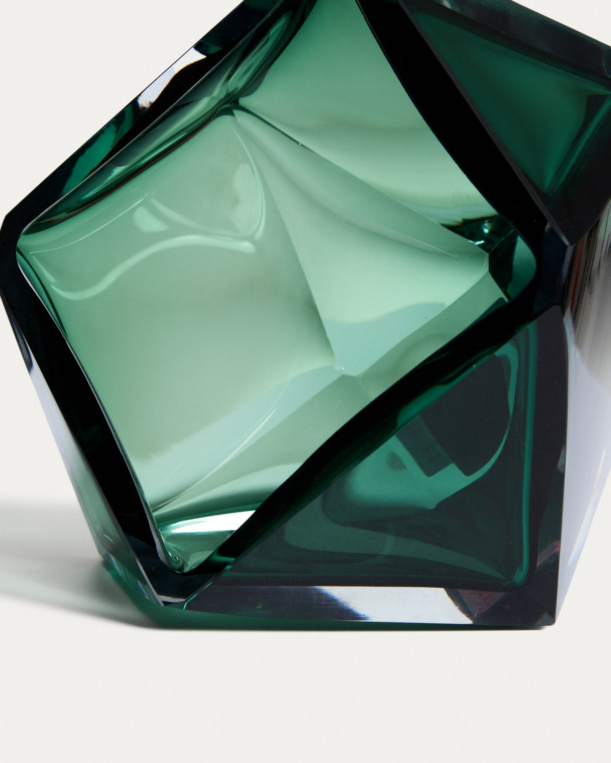 Facettierter Tafelaufsatz aus smaragdgrünem Glas mit runder Öffnung, mundgeblasen gefertigt, auf weissem Hintergrund fotografiert.