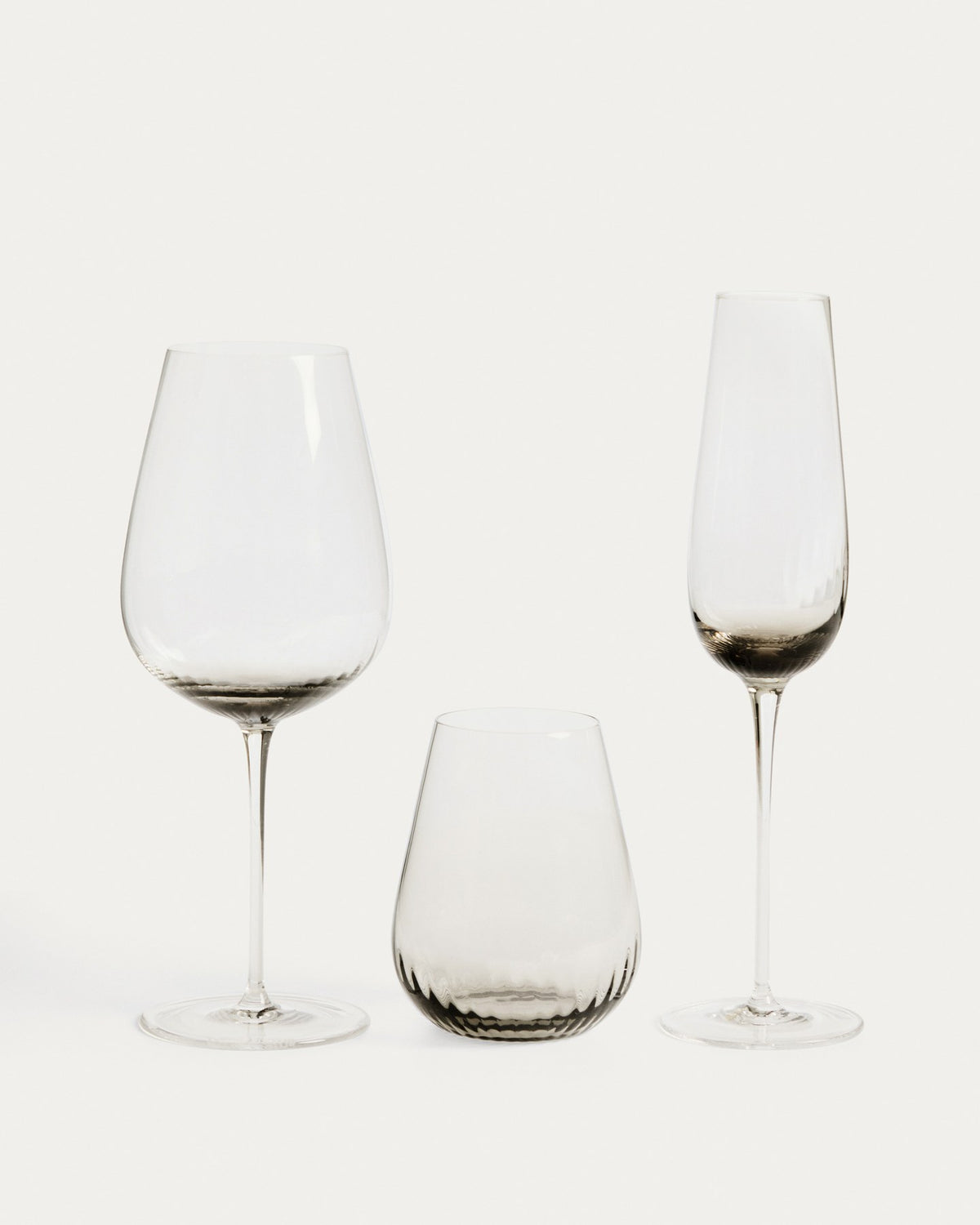 Hellgraues Trinkglas aus 100% Glas mit abgerundeter Basis und grauem Boden, klare Oberfläche, kompakte Form für Getränke.