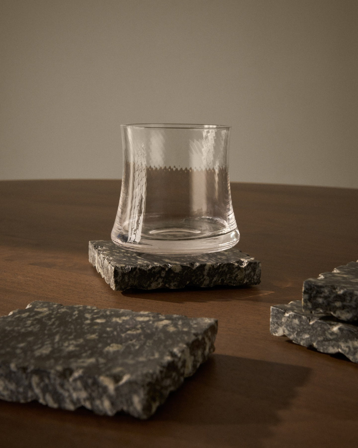 Vier quadratische Untersetzer aus dunkelgrauem Granit, handgefertigt mit natürlicher Marmorierung und individueller Textur, im Set von Kave Home.
