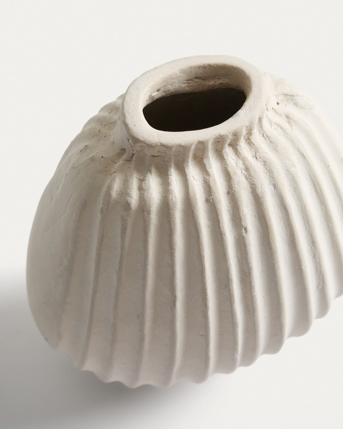 Handgefertigte Vase aus Pappmaché in der Farbe Ecru mit abgerundeter Form und feinen Relief-Linien auf der gesamten Oberfläche.