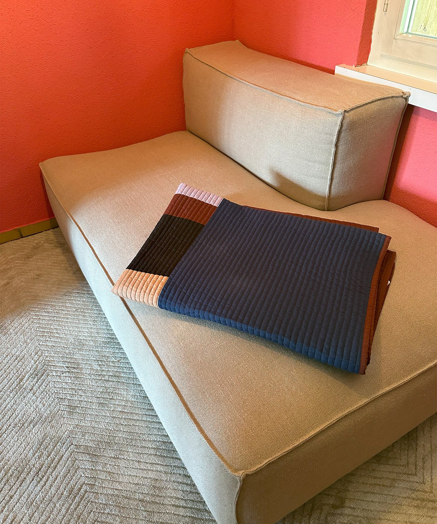 Chaise Longue in einem Wohnzimmer mit roter Wand