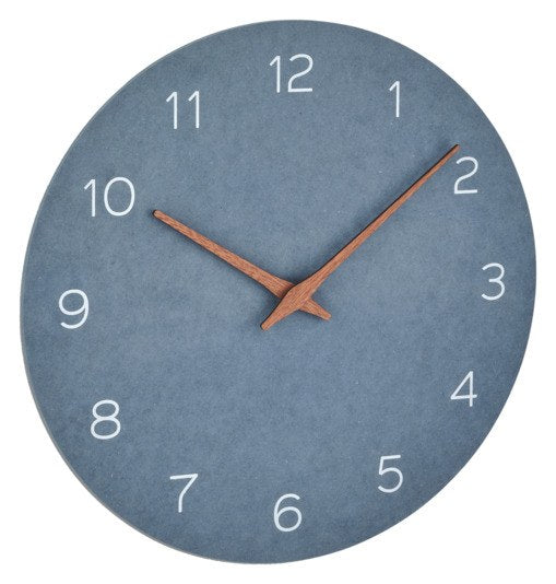 Runde Wanduhr mit taubenblauem MDF-Ziffernblatt, Zeigern aus Walnussholz und schlichtem Rahmen, an heller Wand montiert.