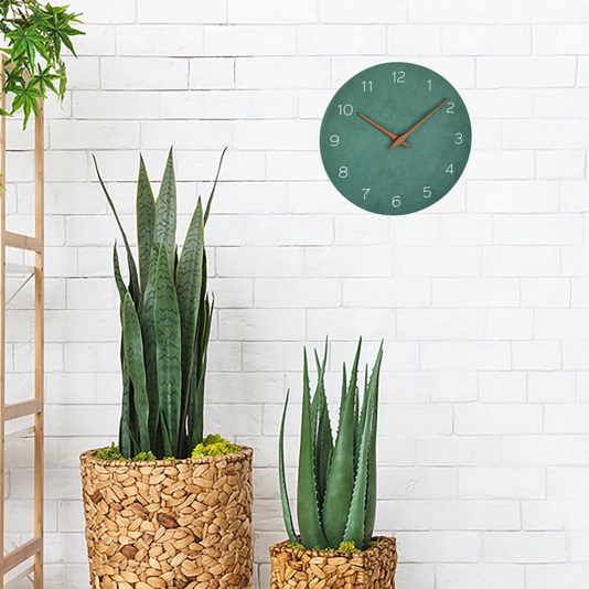 Runde TFA Wanduhr in Jadegrün mit Zeigern aus Walnussholz und Ziffernblatt aus MDF in Naturtönen, minimalistisches Design an weisser Wand.