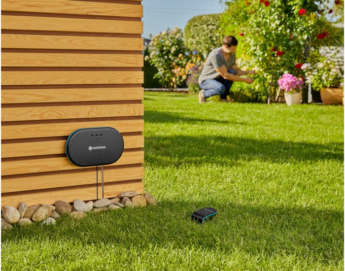 Schwarzes GARDENA Set Smart Irrigation Control mit Steuereinheit, Gateway, Bodenfeuchtesensor, LAN-Kabel und Netzteil auf weissem Hintergrund
