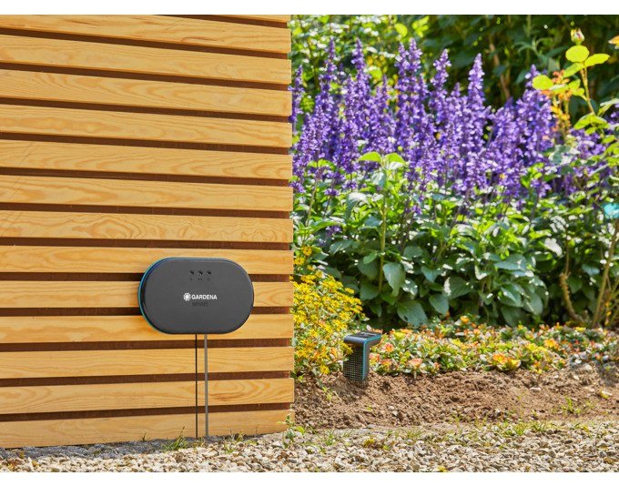 Schwarzes GARDENA Set Smart Irrigation Control mit Steuereinheit, Gateway, Bodenfeuchtesensor, LAN-Kabel und Netzteil auf weissem Hintergrund