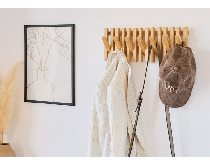 Wandgarderobe aus Bambus in Natur mit mehreren Kleiderhaken, montiert an einer Wand, zeigt warme Holzstruktur und schlichte Form.