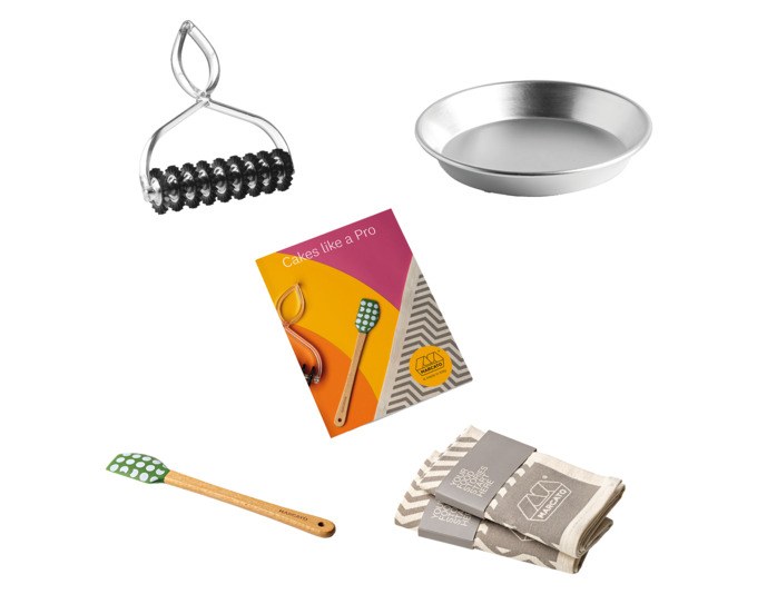 Set aus MARCATO Pasta Bike, Aluminium-Kuchenblech, Teigschaber, Rezeptheft und Tischsets in den Farben Silber, Natur und Braun.
